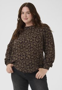 Schwarze Bluse mit einem beigen Blumenmuster, langärmlig und mit rundem Halsausschnitt. Der Stoff hat ein strukturiertes Aussehen.