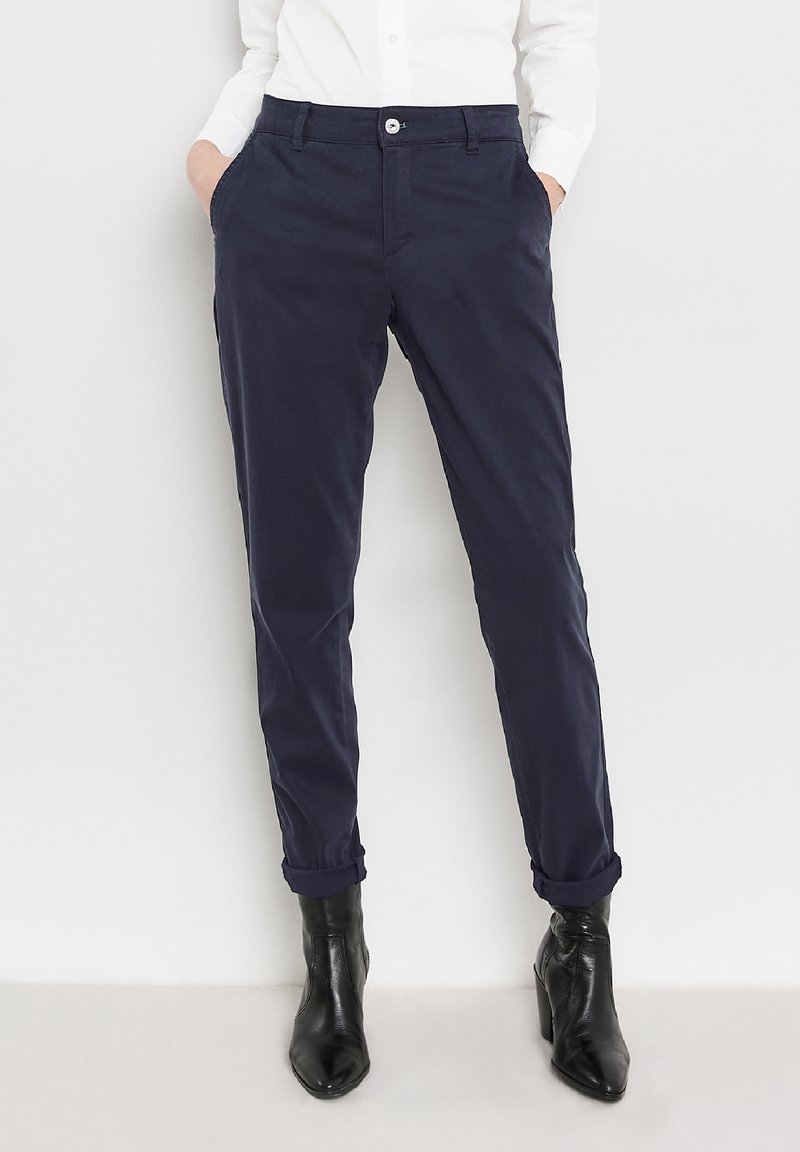 Navy chinos with a tailored fit, featuring side pockets, a button closure, and rolled cuffs, paired with black ankle boots.
