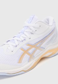 Baskets blanches avec une tige en maille texturée, accents violet clair et une semelle en caoutchouc avec une teinte jaunâtre et le logo Asics.