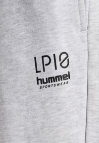 Grå sportstøjsbeklædning med en blød tekstur. Indeholder sort trykt logo "LPI10" og "hummel SPORTSWEAR" på forsiden.
