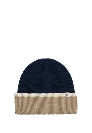Knit beanie with three color blocks: navy blue top, thin white middle band, and wide beige cuff with a small square fabric tag.