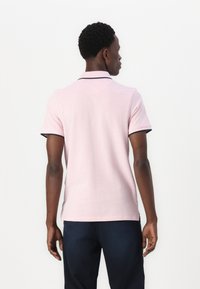 Roze polo shirt met korte mouwen, voorzien van een kraag met marineblauwe accenten, gemaakt van textuurstof. Het ontwerp bevat een rechte zoom.