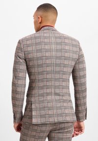 Beige kariertes Herren-Sakko mit navyblauen und burgunderroten Linien. Textilstruktur mit einem kontrastierenden burgunderroten Kragen und taillierterPassform.