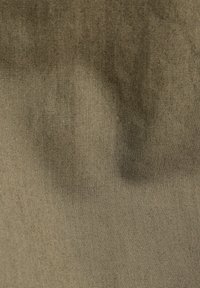 Tan tyg med subtila rynkor och en fint vävd struktur synlig över ytan.