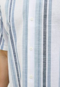 Camicia con bottoni caratterizzata da righe verticali in blu chiaro, blu scuro e bianco. Realizzata in un tessuto testurizzato con una finitura morbida.