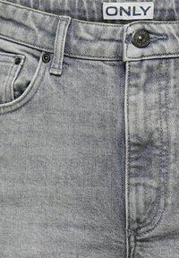 Grå denimjeans med en falmet tekstur, med en knappelukking, beltestropper, og en lomme på venstre side. Merkelapp øverst.