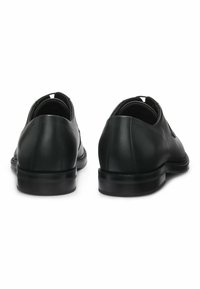 Scarpe di pelle nera con finitura liscia, punta rotonda, profilo basso e suola in gomma. Presentano cuciture minime e un tassello per il rialzo sul retro.