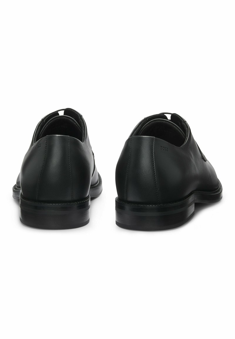 Zwarte leren schoenen met een gladde afwerking, ronde neus, laag profiel en rubberen zool. Voorzien van minimale stiksels en een lus aan de achterkant.