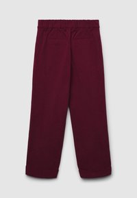 Burgunderfarbene Cord-Hose mit weitem Bein, elastischem Bund und zwei Vorderseiten-Taschen. Die Hosenbeine sind am Saum umgeschlagen.
