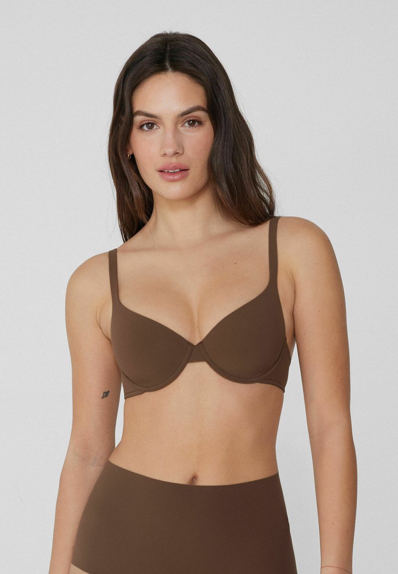 Brązowy biustonosz z formowanej ściągaczki, z regulowanymi ramiączkami i gładką teksturą, posiadający bezszwowe miseczki i minimalne zdobienia.