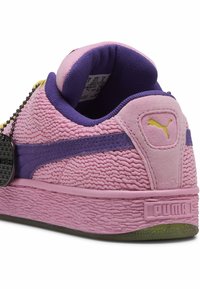 Lyserødt struktureret sneakersko med lilla accenter, der har en skumkrave, struktureret gummisål og et sort mærke på siden.
