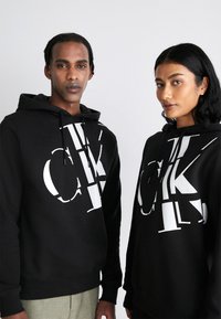 Calvin Klein Jeans - REGULAR HOODIE SCATTERED LOGO UNISEX - Sweatshirt - black Miniatyrbilde 1