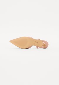 Sandal décolleté en cuir verni rose pâle avec un bout pointu, une fine bride de cheville et une semelle en caoutchouc texturé. Marque ALDO en dessous.