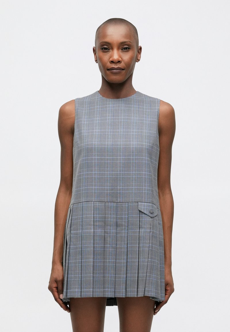 Pelēku svītru bez piedurknēm kleita ar izplestu svārku, apaļu kaklu un sānu kabatu detaļām. Audums izceļas ar zilo un melno līniju sajaukumu.