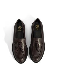 Bordeaux leren loafers met kwastaccenten, gladde textuur, ronde neus en zwarte rubberen zool. Logo in goud geëmbosseerd op de binnenzool.