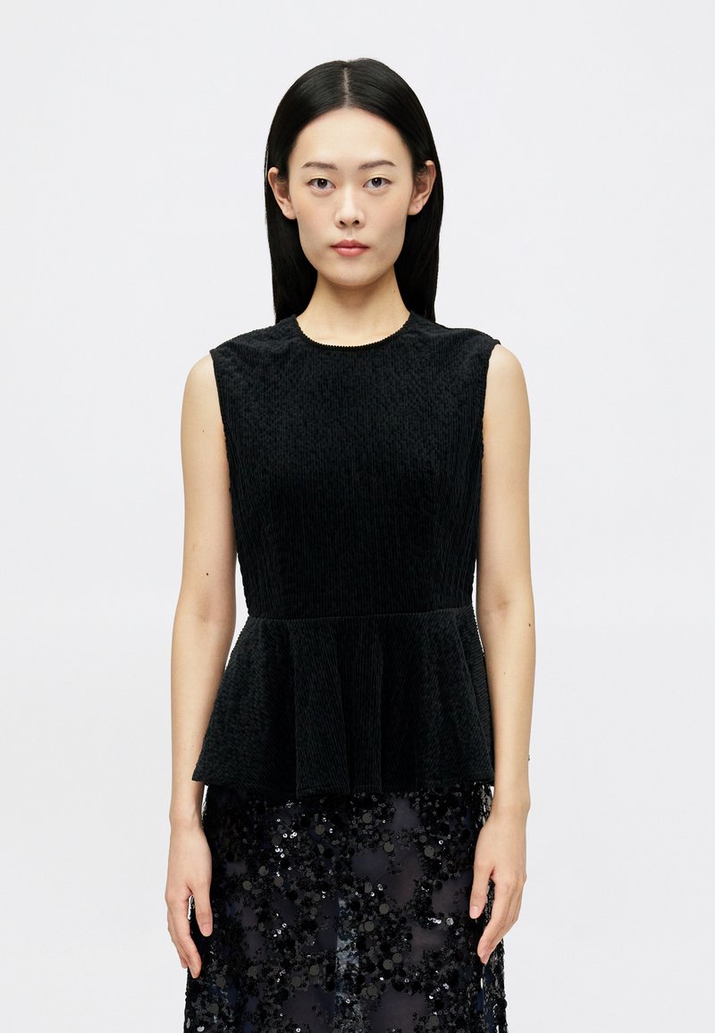 Top negru fără mâneci, dintr-un material texturat, cu un tiv peplum și un decolteu rotund. Purtați-l peste o fustă strălucitoare, brodată cu paiete.