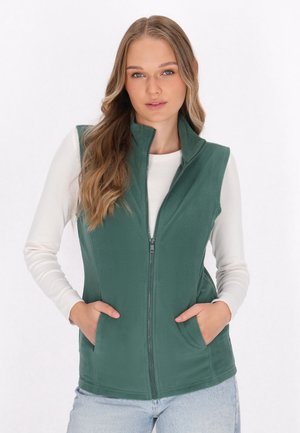 Grüne Fleece-Weste mit Kragen, Reißverschluss vorne und Seitentaschen. Getragen über einem weißen Langarmshirt mit glatter Textur.