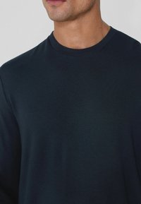 Námořnické tričko s dlouhým rukávem vyrobené z měkké bavlny, s kulatým výstřihem a hladkým povrchem, bez viditelných vzorů nebo log.