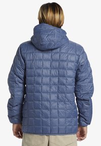 Blauer, gesteppter Pufferjacke mit Kapuze, aus leichtem, glänzendem Material und quadratischem Steppmuster. Die Rückansicht zeigt elastische Bündchen.
