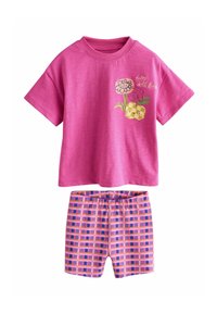 Rózsaszín rövid ujjú póló virágos grafikával és szöveggel, mintás rövidnadrággal párosítva, amely rózsaszín, narancssárga és kék téglalapokat tartalmaz.