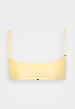 Gul bandeau-bh med tynne stropper, glatt stoff, minimalistisk design og sømløs konstruksjon. Ingen merkbare maskinvare eller mønstre.