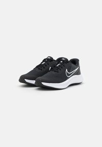 Scarpe sportive nere con tomaia in rete, logo swoosh bianco, suola imbottita e suola testurizzata per aderenza. Presentano un design con lacci.