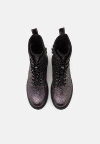 Bottines noires et violettes métalliques avec une surface texturée, un devant à lacets et des languettes de tirage au niveau des chevilles. Semelles plates et durables.