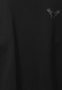 Tissu noir avec un logo subtil de tête d'orignal gris foncé en haut à droite.