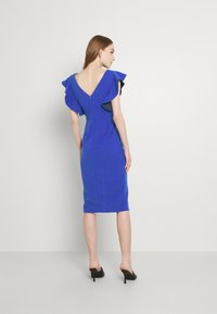Vestido azul justo com mangas de babado e detalhe nas costas em V, feito de tecido suave. Apresenta um fecho zip oculto nas costas e um design até ao joelho.