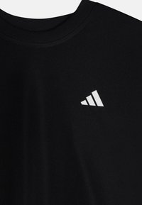 Camiseta de algodón negra con cuello redondo y un logo de Adidas en blanco compuesto por tres barras paralelas dispuestas en forma triangular.