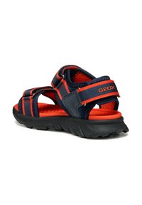 Tmavě modré a oranžové sandály s síťovinovými pásky, gumovou podrážkou a nastavitelným zapínáním. Texturovaná stélka a značka na zadním pásku.