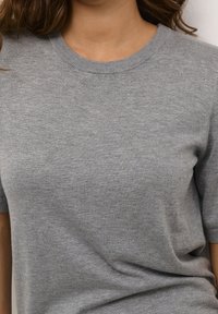 Šedý pletený svetr s krátkými rukávy a kulatým výstřihem, s jemnou texturou pro ležérní a pohodlný vzhled.