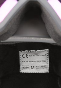 Mærket på det sorte beskyttelsesudstyr til vintersport viser produktdetaljer: CE-certificering, klasse, størrelse (52/56), model (38B4677), vægt (510g).
