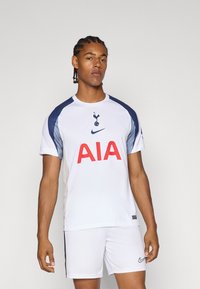 Hvid sportsjersey med blå accenter, med "AIA" i rødt på fronten og et holdlogo ovenfor. Båret med matchende hvide shorts og Nike-branding.
