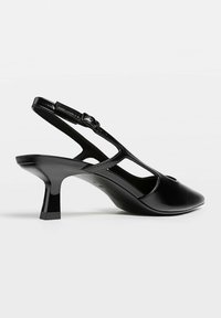 Svart högblank läder slingback sko med kitten heels, spetsig tå och justerbar spänne.