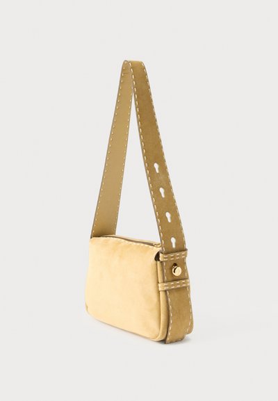 Μικρή μπεζ τσάντα ώμου από σουέντ με φαρδιά ραμμένη ράβδο που διαθέτει οπές σε σχήμα κλειδαρότρυπας και λεπτομέρεια με χρυσό κουμπί.