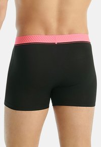 Svarta boxershorts med en texturerad rosa midja, med en slät finish och minimalistisk design. Inga synliga logotyper eller mönster.