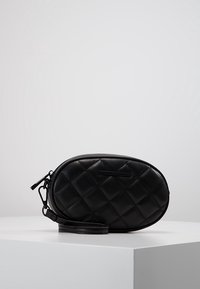 Bolso de hombro negro de acolchado con acabado de cuero suave, forma ovalada, cierre de cremallera y correa ajustable. Detalle sutil del logo en la parte frontal.