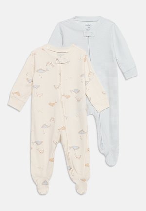 Deux pyjamas bébé avec pieds, l’un crème avec des imprimés de baleines bleues et marron, l’autre bleu clair avec de fines rayures blanches, tous deux à manches longues et fermetures éclair devant.