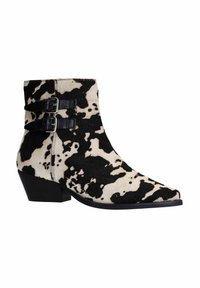 Bottines à imprimé vache en noir et crème, avec deux boucles en cuir noir, un bout pointu et un petit talon empilé. Matériau en fourrure texturée.