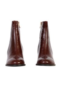 Bottes chevilles en cuir marron avec une finition brillante, fermeture éclair sur le côté, et une forme élégante et effilée avec une semelle plate.