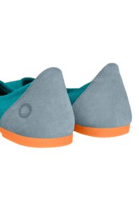 Šedé semišové baleríny s oranžovou podrážkou a tyrkysovým interiérem. Zadní strana má trojúhelníkový design a malou znakovou ozdobu.