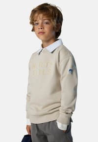 Sudadera beige con "NORTH SAILS" bordado en beige claro, cuello redondo, mangas largas y color blanco de camisa asomando.