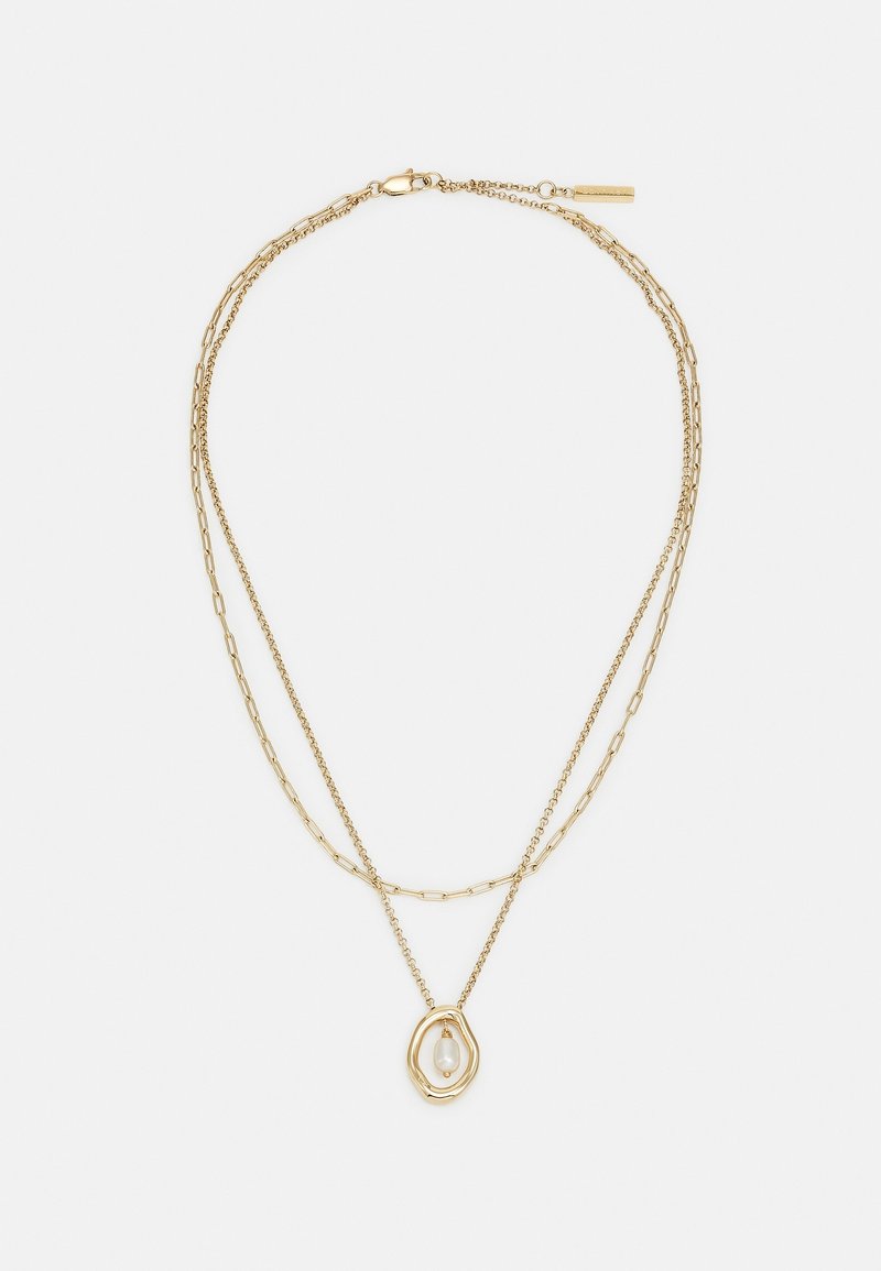 Collier chaîne dorée superposée avec deux styles de maillons différents et un pendentif présentant un cadre doré irrégulier tenant une perle blanche.