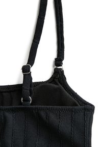 Reggiseno nero con tessuto testurizzato caratterizzato da righe verticali, spalline regolabili con accessori in metallo e rivestimento morbido per comfort.