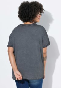 Grå t-shirt med korte ærmer i en løs, afslappet pasform og oprullede ærmer. Har en rund halsudskæring og en glat, blød tekstur.