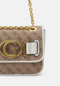 Ruskeakuvioinen käsilaukku, jossa on kullanväriset metalliosat, ketjuhihna ja näkyvä logo. Valmistettu teksturoidusta kankaasta ja nahkaisista yksityiskohdista.