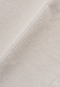 Manchestertyg i mjukt vitt, med en ribbad textur och jämnt fördelade vertikala räfflor, vilket skapar ett mjukt och taktilt utseende.