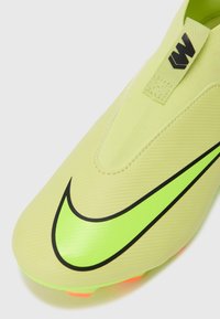 Korki do piłki nożnej Nike w intensywnym żółtym kolorze z dużym czarnym Swooshem. Smukły design z teksturowaną cholewką i jasnopomarańczowymi kołkami na podeszwie.