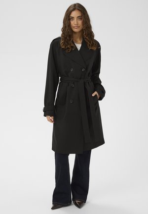 Czarny płaszcz trencz o dwurzędowym kroju, z paskiem w talii i ozdobnymi guzikami. Miękka tkanina, długie rękawy, zestawiony z ciemnymi spodniami o rozszerzanych nogawkach.